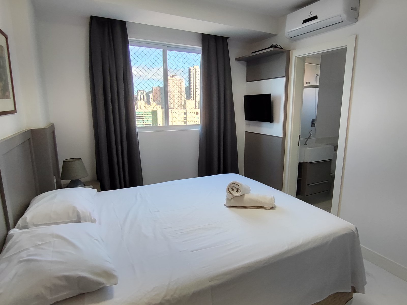 Suíte com cama de casal e TV de parede