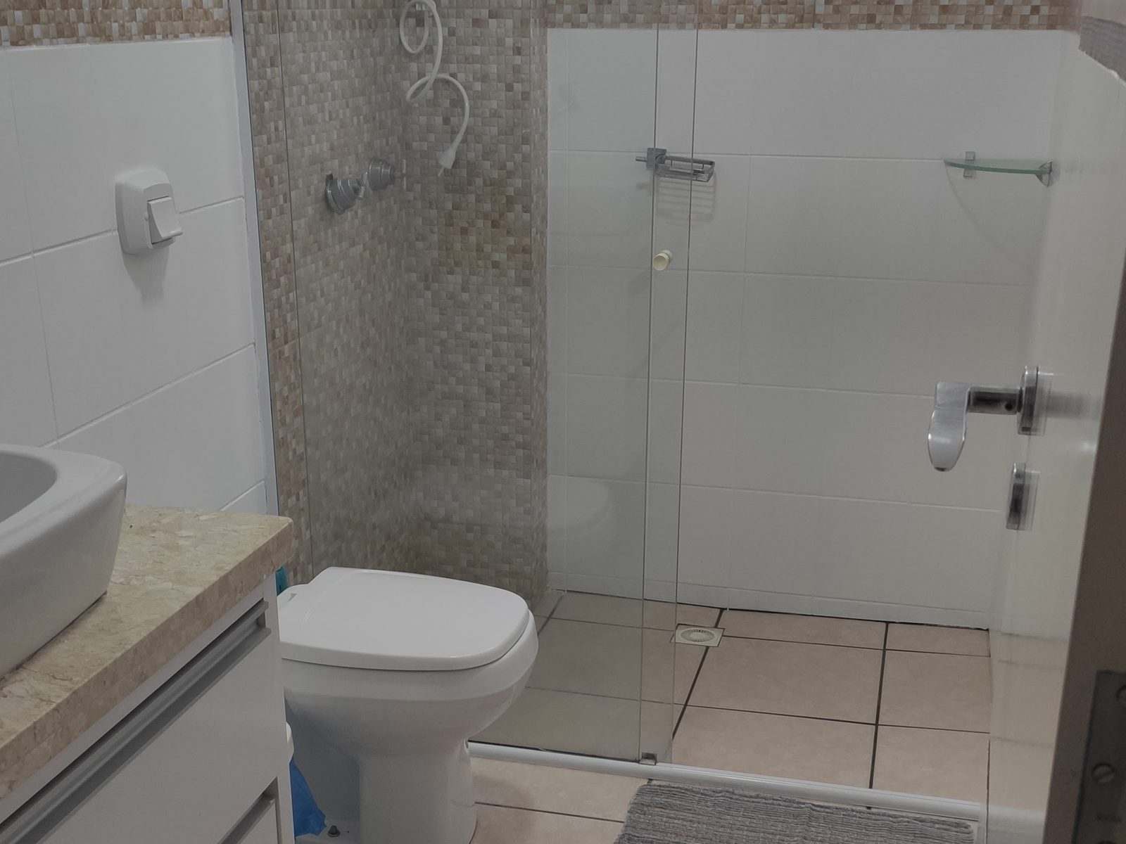 Banheiro com box de vidro e bancada com cuba de apoio