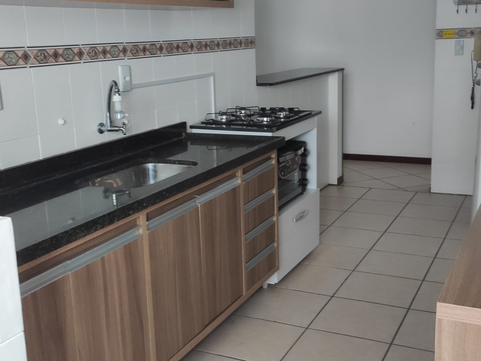 Cozinha separada com fogão, bancada de granito e armários