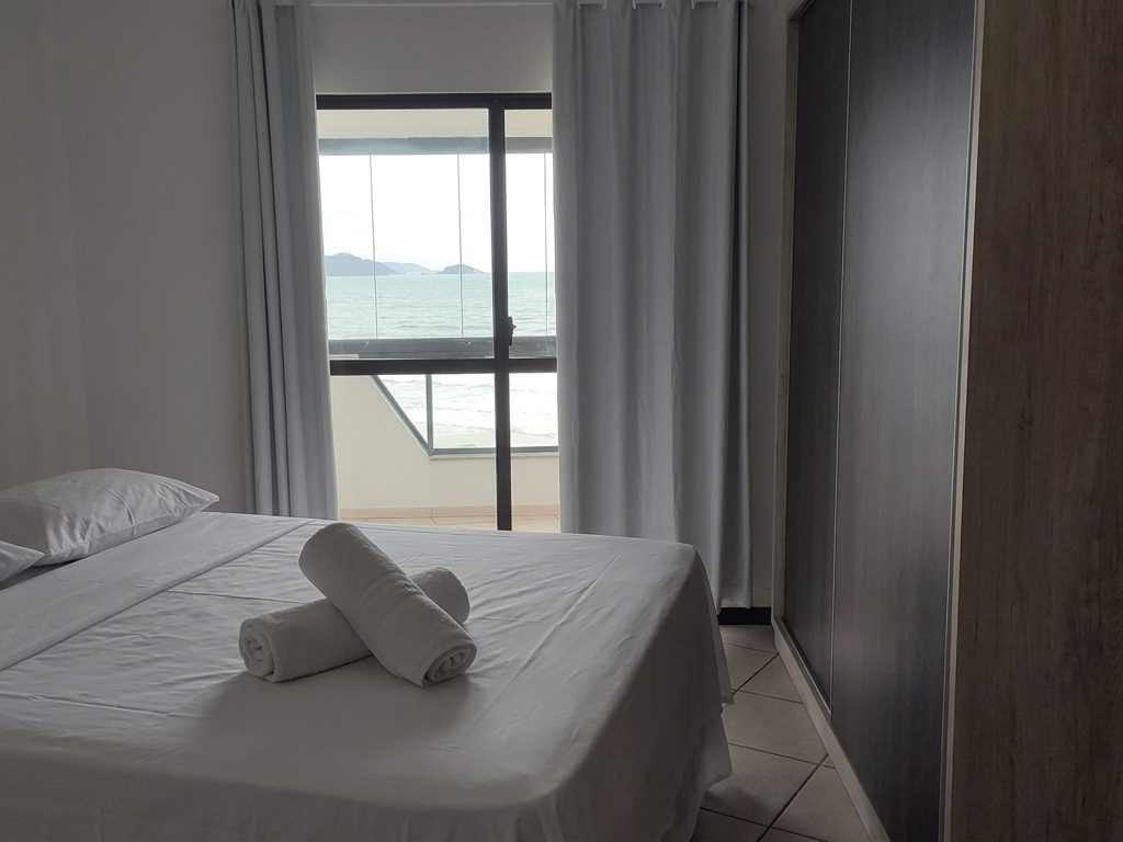 Quarto com cama de casal, armário e sacada com vista do mar