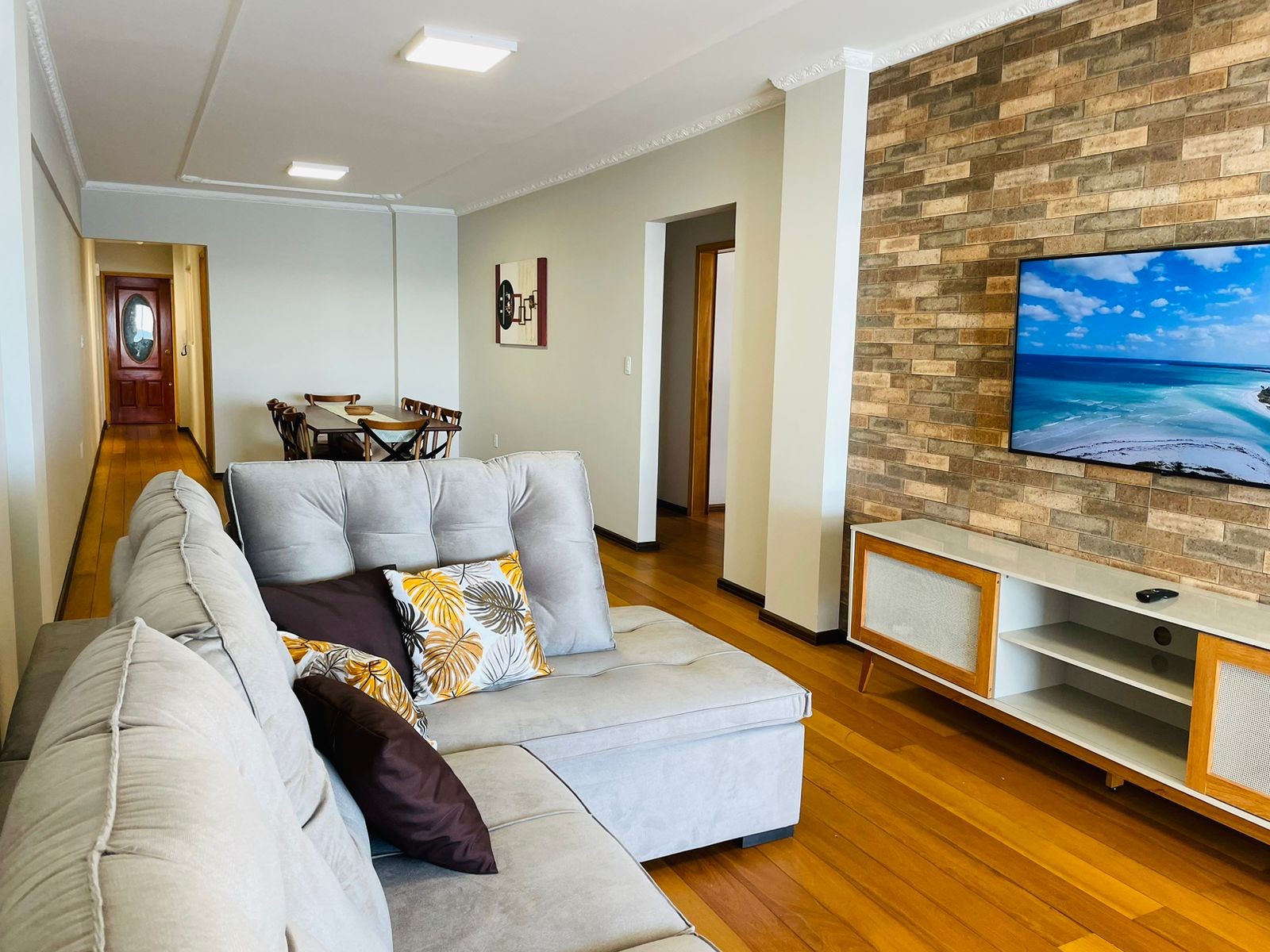 Sala de estar com sofá de canto e parede de destaque com TV