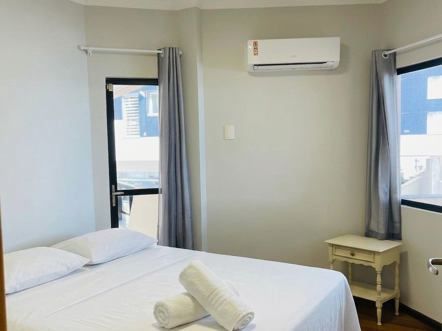 Suíte com cama de casal e criado-mudo bege