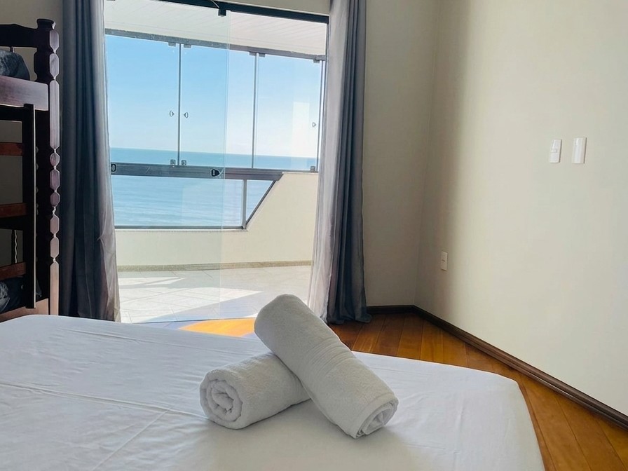 Suíte com cama de casal e vista lateral do mar pela janela