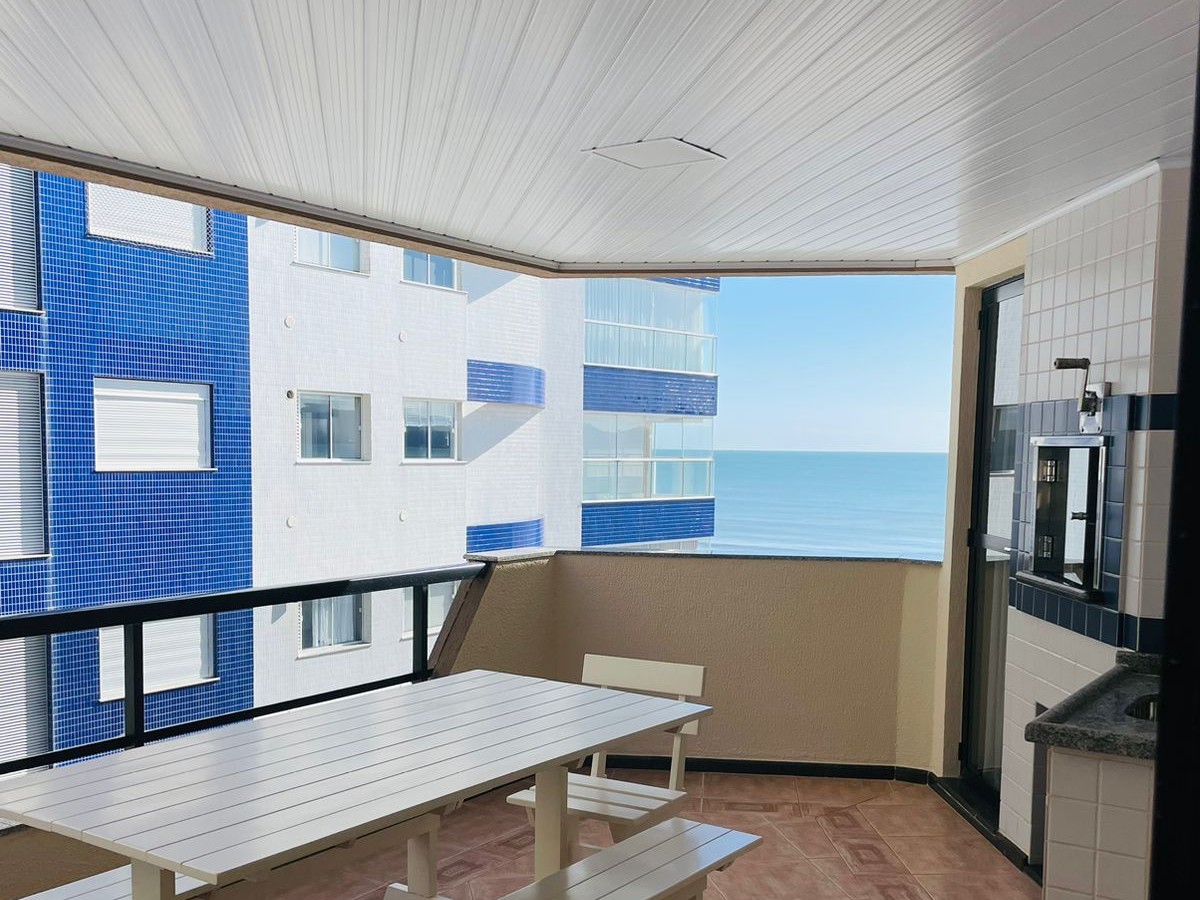 Terraço privativo coberto com mesa de madeira e vista pra orla