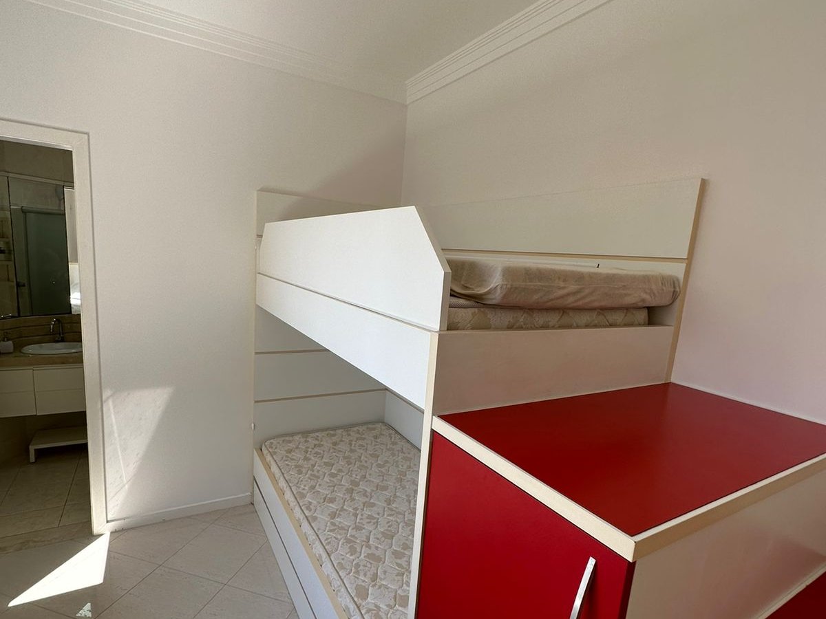 Quarto com treliche (beliche) em vermelho e branco, banheiro próprio ao lado