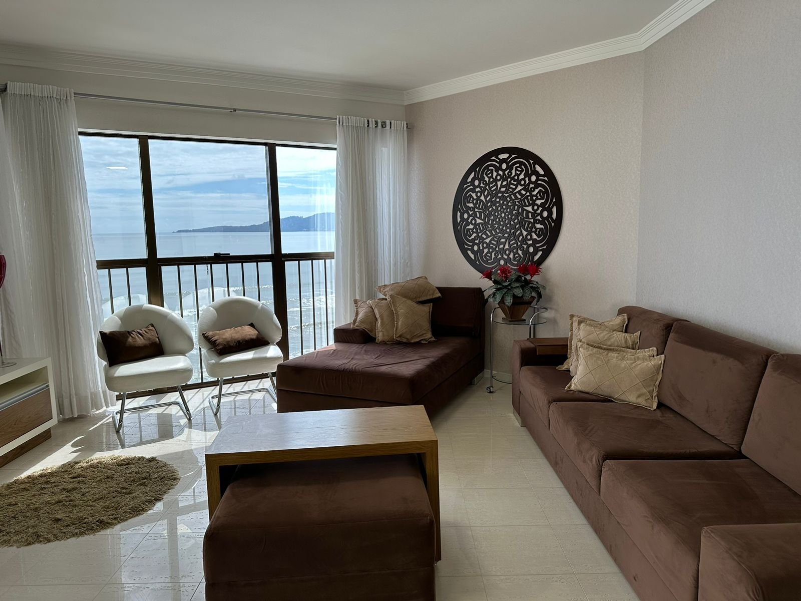 Sala de estar com sofá de canto e poltronas, vista para a orla