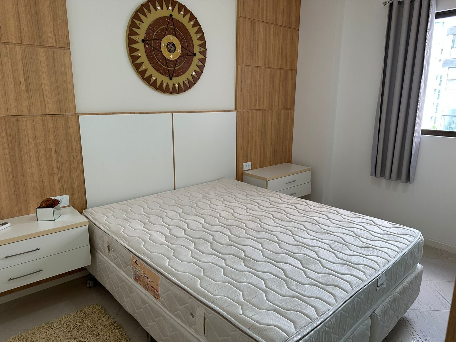 Suíte com cama de casal e medalhão decorativo na parede
