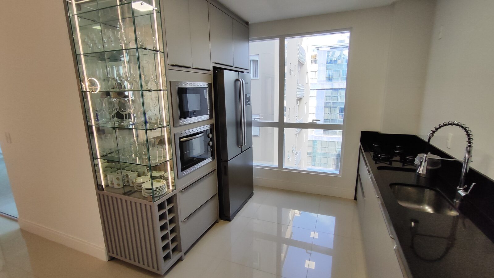 Cozinha equipada com geladeira, cooktop e coifa embutidos