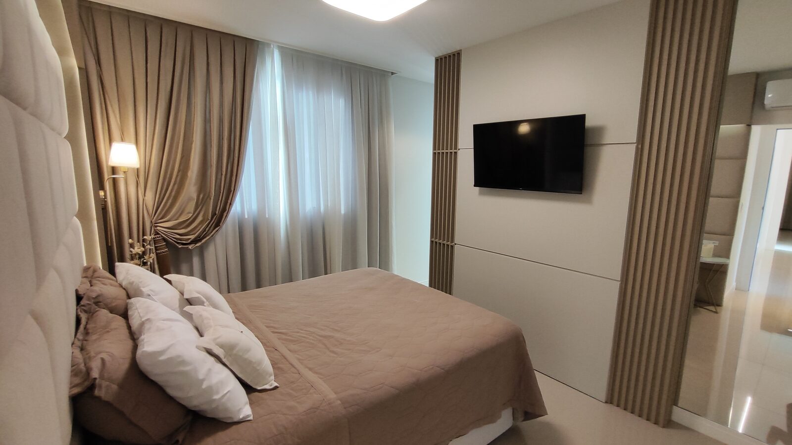 Suíte com painel de TV e armário espelhado