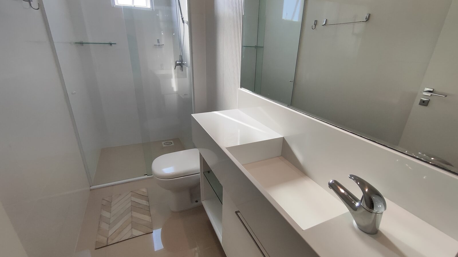 Banheiro com box de vidro e bancada dupla de mármore