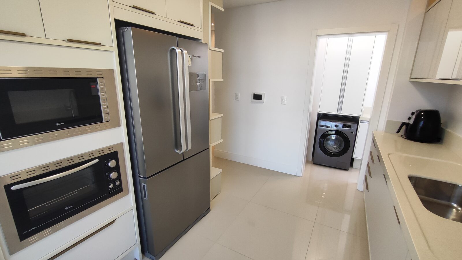 Cozinha gourmet equipada com geladeira, forno e área de serviço