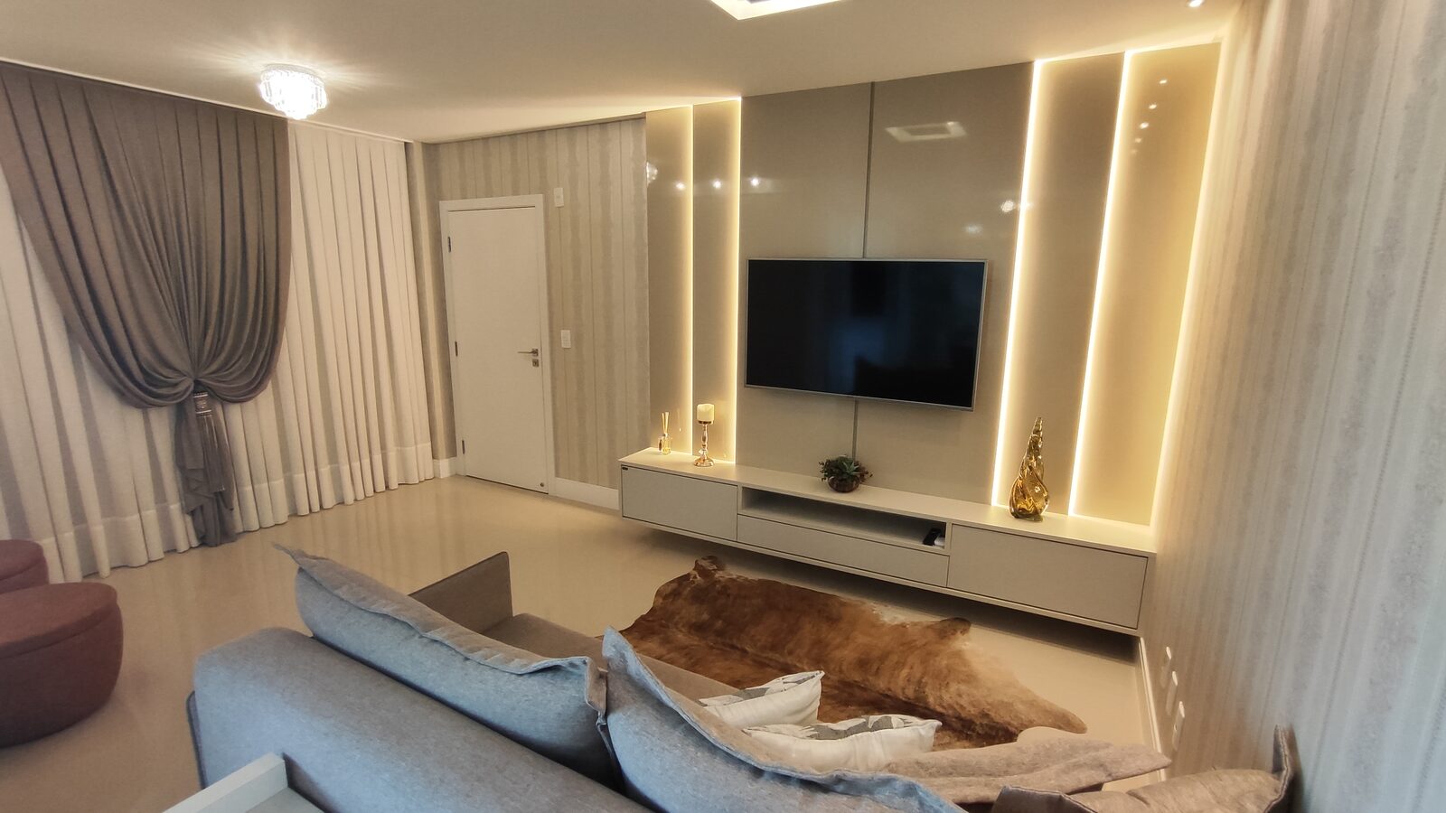 Sala de estar com painel de TV e tapete de pelo