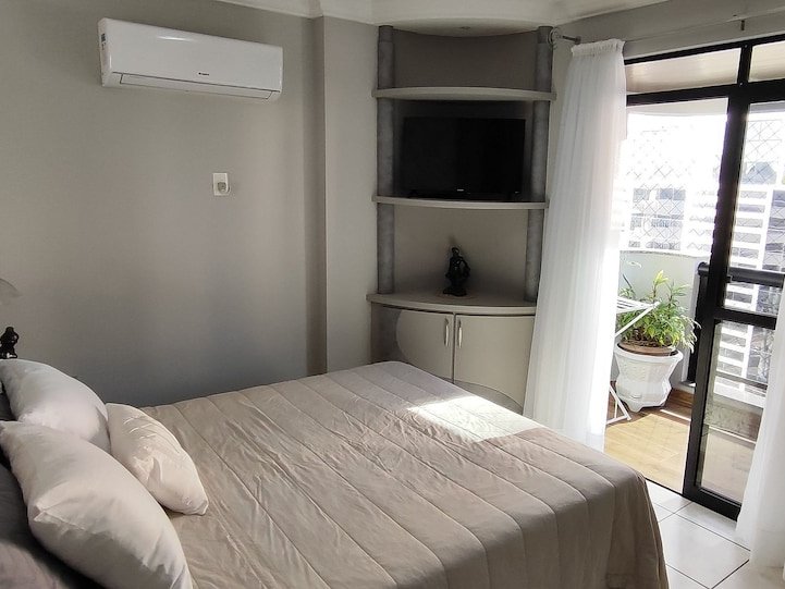 Quarto com cama de casal, namoradeira e porta para a varanda