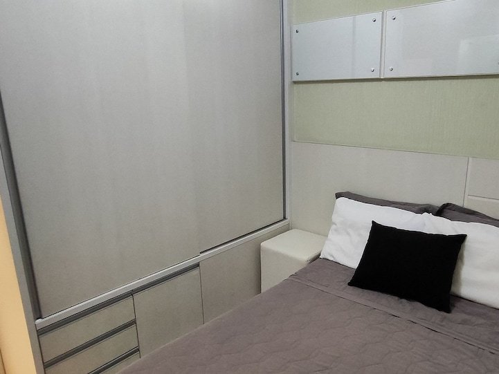 Quarto com cama de casal e parede verde-clara
