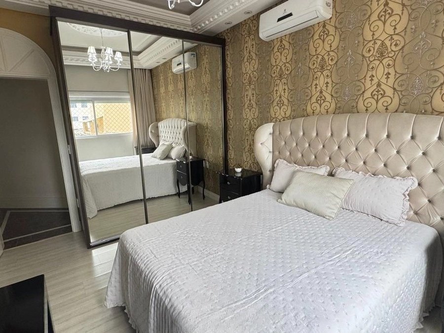 Suíte com papel de parede dourado, cabeceira capitonê e closet espelhado